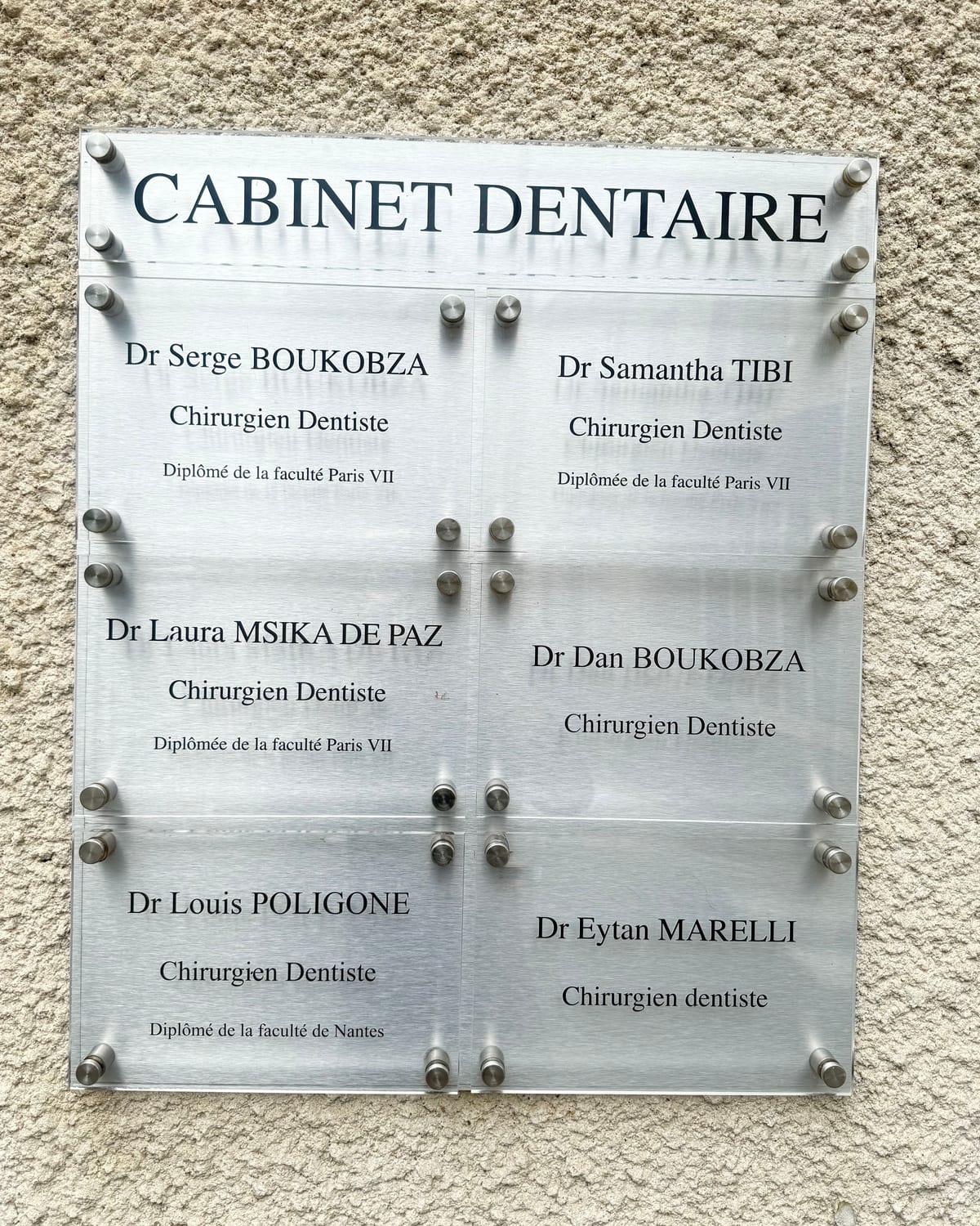 La plaque « Cabinet dentaire » fixée sur la façade, à gauche de la porte d'entrée, avec les noms des chirurgiens-dentistes